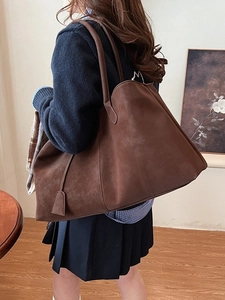 Large vintage brown matte tote bag shown on shoulder of model for a stylish casual look
