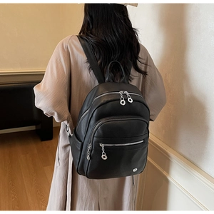Detailed close-up of a black lychee texture leather backpack with silver metal zippers