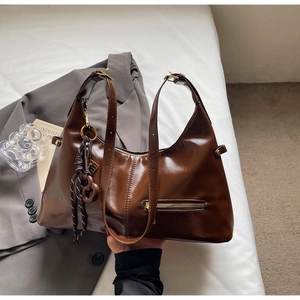 Détail du sac sous l'aisselle en cuir marron foncé avec boucles dorées et breloque