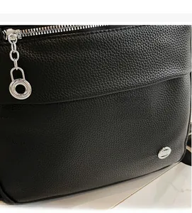 Close-up of silver zipper and round chain pull on black lychee grain leather backpack
