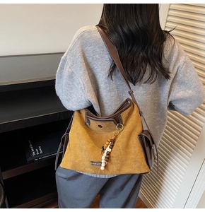 Detail of tan faux suede tote bag with boho tassel charm and deep brown leather trim