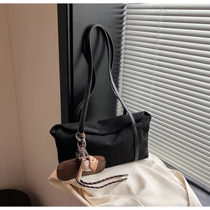 Détail du cabas en daim noir avec des breloques de baseball et de gant sur la bandoulière