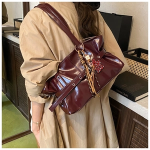 Gros plan sur un sac bandoulière en cuir plissé bordeaux avec breloque léopard chic