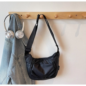 Close-up of black Oxford cloth crossbody bag hanging with daily fashion accessories