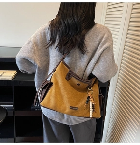 Mustard yellow suede tote bag with leather piping and decorative beads on a model
