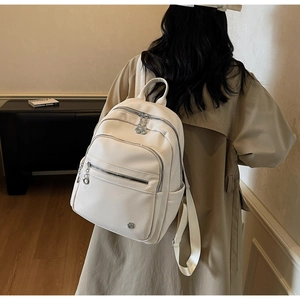 Close-up of litchi grain leather texture and silver zipper detail on chic beige backpack