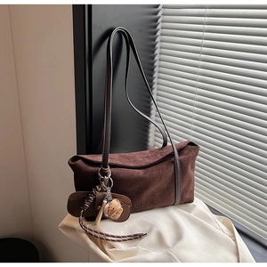 Détail du sac porté épaule en daim marron foncé avec charm baseball et logo embossé