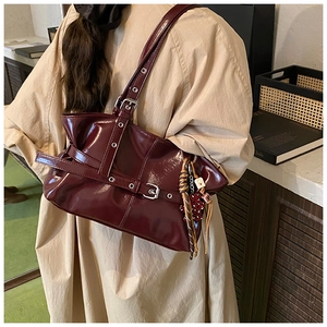 Détail du sac à bandoulière en cuir verni bordeaux avec sangles à boucle et plis