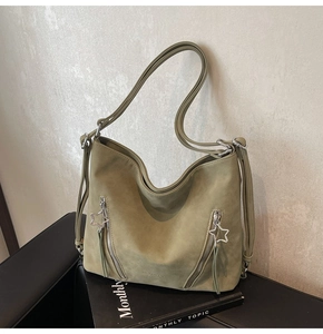 Detailed macro view of olive green tote bag featuring star zippers and fringe tassels