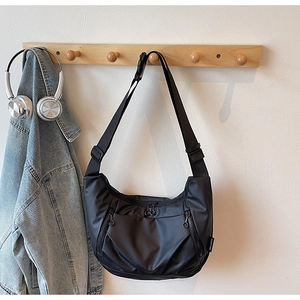 Macro detail of black nylon crescent bag featuring side zipper pockets and logo label