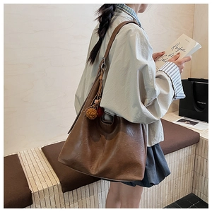 Detail of dark brown tote bag with decorative tassel and natural leather texture