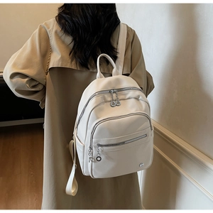 Back view of a creamy white pebbled leather backpack with silver zippers and multi-pockets