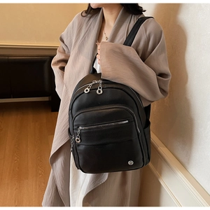 Detail of minimalist black pebbled leather backpack with silver zippers and front pocket