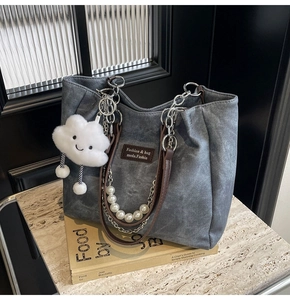 Detail der blauen Denim-Tasche mit braunem Kunstlederriemen, Silberkette und Perlen-Dekor
