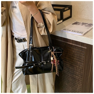 Détail du sac à bandoulière noir brillant avec boucle de ceinture et charms vintage