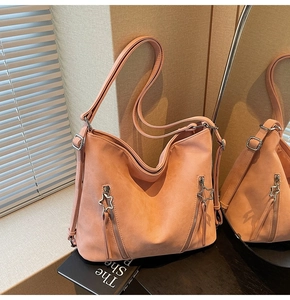 Detail of peach pink tote bag showing star-shaped zipper pulls and fringe tassels