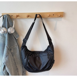 Detail of black nylon crescent bag featuring multi-zipper pockets and adjustable strap