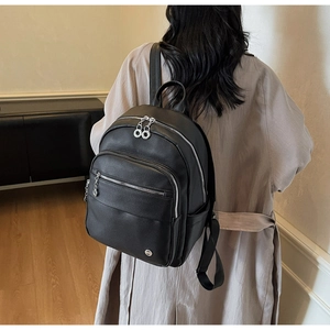 Model wearing a black pebble grain leather backpack with multiple zipper compartments