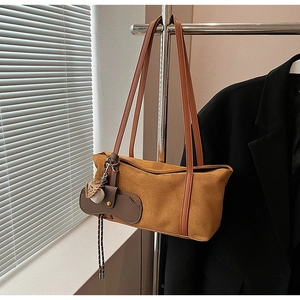 Gros plan sur un sac sous le bras en daim marron avec pendentif baseball unique