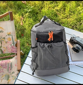 Détail d'un sac à dos de randonnée gris avec poche filet sur une table de camping