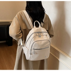 Rear view of model wearing a minimalist cream leather backpack with lychee grain texture