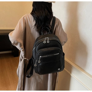Lifestyle shot of black large capacity faux leather backpack with silver zippers