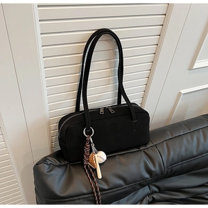 Nahaufnahme der schwarzen Baguette-Tasche mit Doppelreißverschluss und Baseball-Anhänger