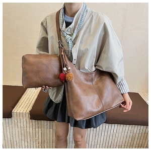 Close-up of vintage brown tote bag set with adjustable strap and colorful pom-poms