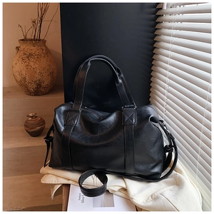 Close-up of black pebble leather tote bag showing reinforced handles and textured finish