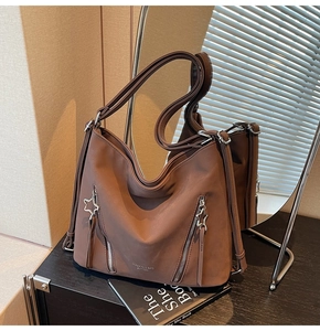 Detail view of brown tote bag with star-shaped metal zippers and textured leather surface