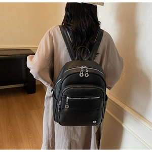 Close-up of black lychee grain leather backpack with silver metal zippers on back