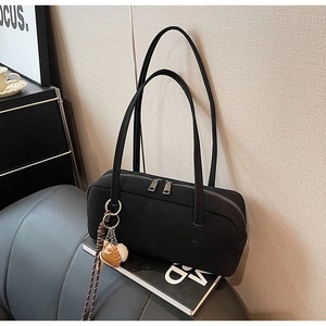 Detailaufnahme einer schwarzen Retro-Baguette-Tasche mit Reißverschluss und Anhänger