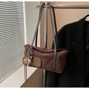 Détail d'un sac à bandoulière en daim marron vintage avec pendentif gant de baseball