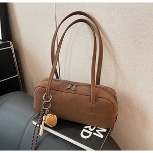 Detailansicht der braunen Wildleder-Baguette-Tasche mit originellem Baseball-Anhänger