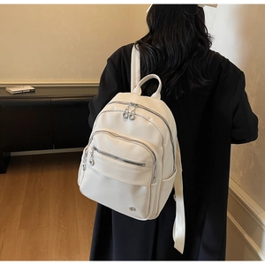 Detailed macro view of ivory pebbled leather backpack with silver zippers and chain detail
