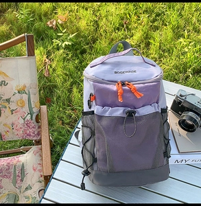 Scène de camping avec sac à dos de randonnée violet et gris et poche en filet