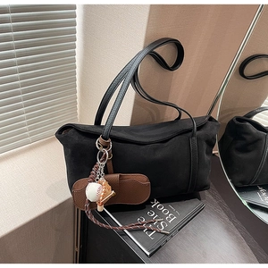 Vue détaillée du sac à bandoulière noir mat avec pendentif de baseball et texture cuir