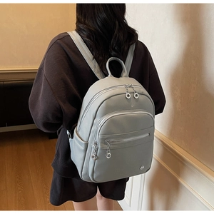 Detailed back view of a grey pebble leather backpack with multiple zipper pockets