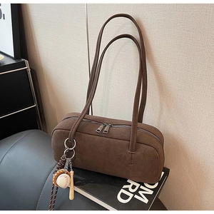 Detailaufnahme der dunkelbraunen Wildleder-Schultertasche mit Doppelreißverschluss und Anhänger