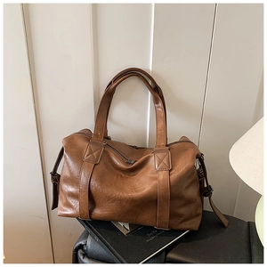 Detailed close-up of dark brown soft leather tote with reinforced handles and buckles