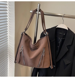 Detail of dark brown tote bag featuring star zipper accents and textured matte finish