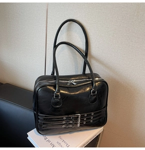 Detail of glossy black vintage leather tote bag with three parallel buckle decorations