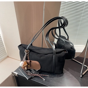 Détail d'un sac à bandoulière en daim noir avec doubles lanières et charm de baseball
