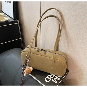 Detail einer moosgrünen Wildleder-Schultertasche mit Doppelreißverschluss und Anhänger