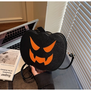 Detail of a black leather pumpkin crossbody bag showing the Jack-o'-lantern design and texture