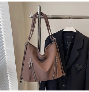 Detail of mocha brown hobo tote bag featuring side zippers and a star charm on a hanger