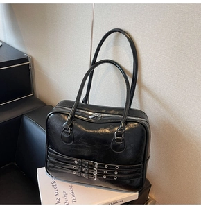 Detail of vintage black tote bag with silver eyelet belts and glossy cracked texture