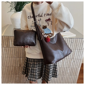 Detail of dark brown faux leather tote bag with small pouch and plush ball charms