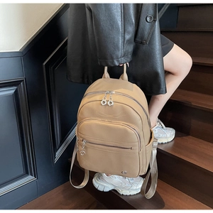 Detail of premium beige lychee leather backpack with metal zipper pull and side pocket