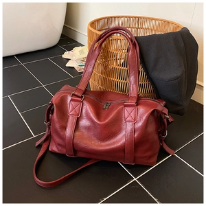 Detail of dark red faux leather travel tote bag with double handles and long strap
